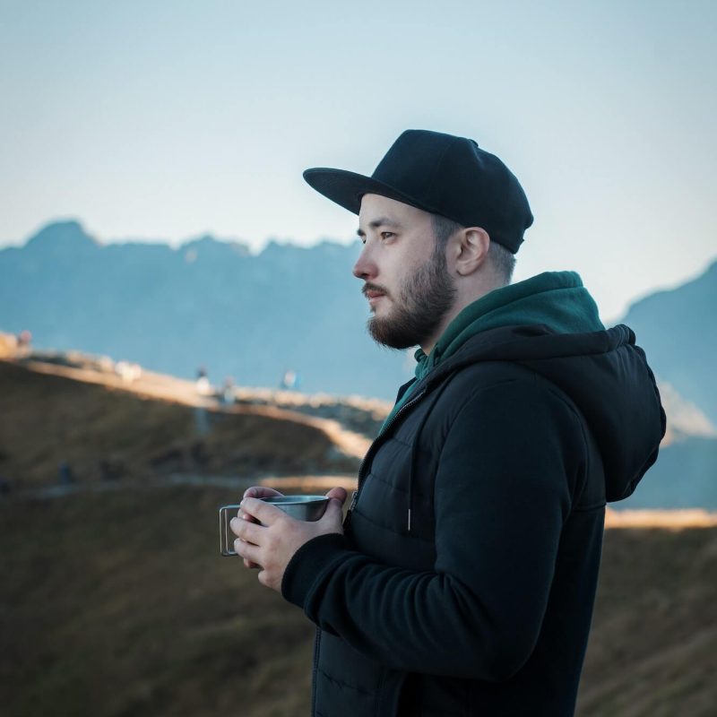 bearded-traveler-man-drinks-tea-or-coffee-from-metal-cup-while-resting-on-a-rock-1.jpg