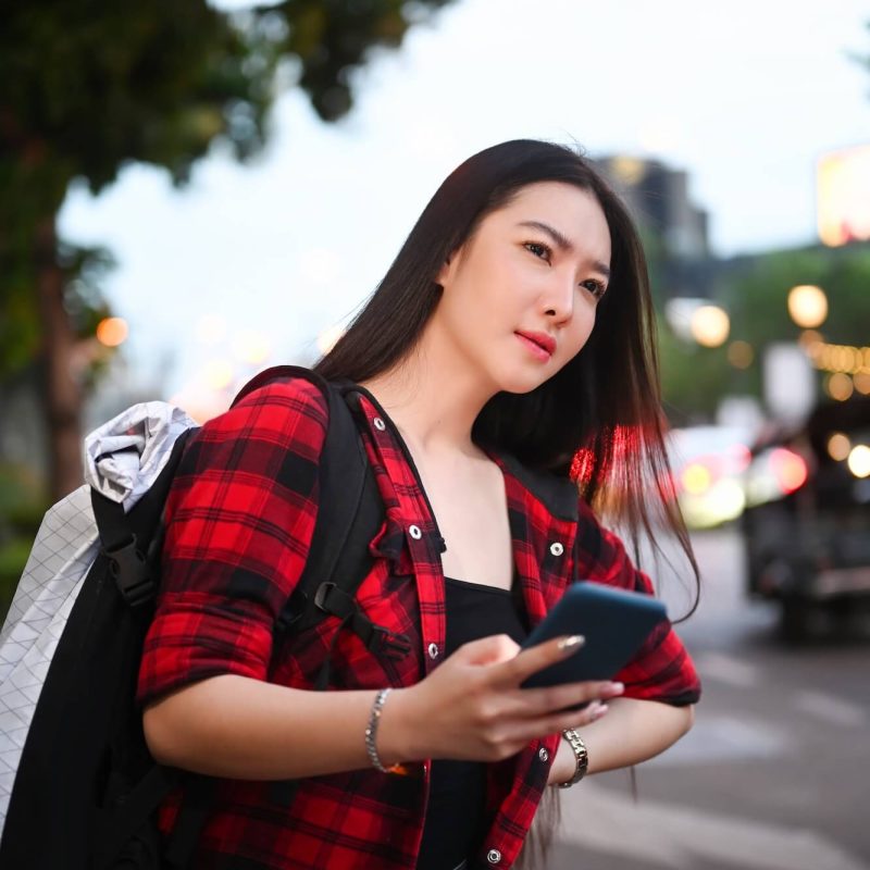 young-female-traveler-with-backpack-using-application-of-taxi-service-on-smart-phone-1-1.jpg